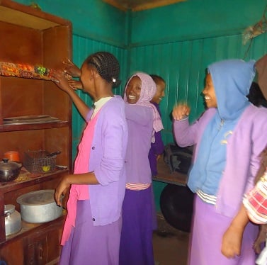 Tizita, left, and two other girls clean a cabinet in their pastry shop.