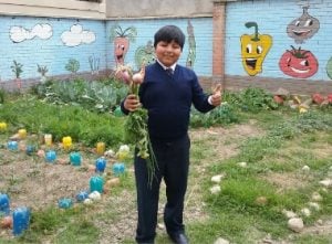 A young boy smiling holding his homegrown crops