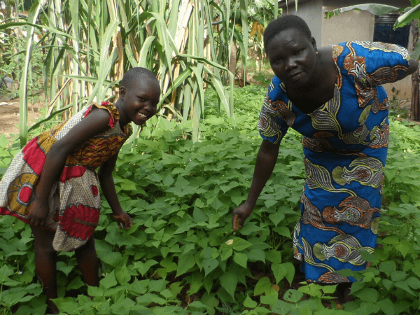 A little girl and her mom smiling in their home garden