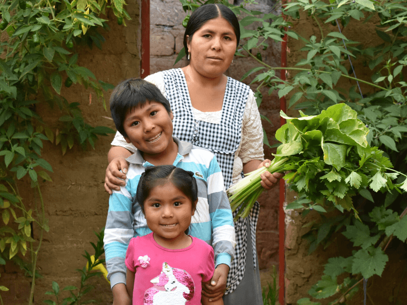 A woman stands in a garden with her young daughter and son
