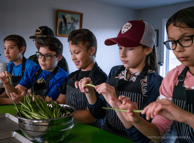 A group of young school kids preparing asparagus in a cooking class